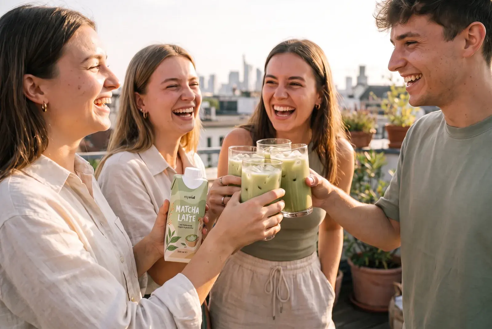 Drei Freunde stoßen auf einer sonnigen Dachterrasse mit Gläsern Iced Matcha Latte an