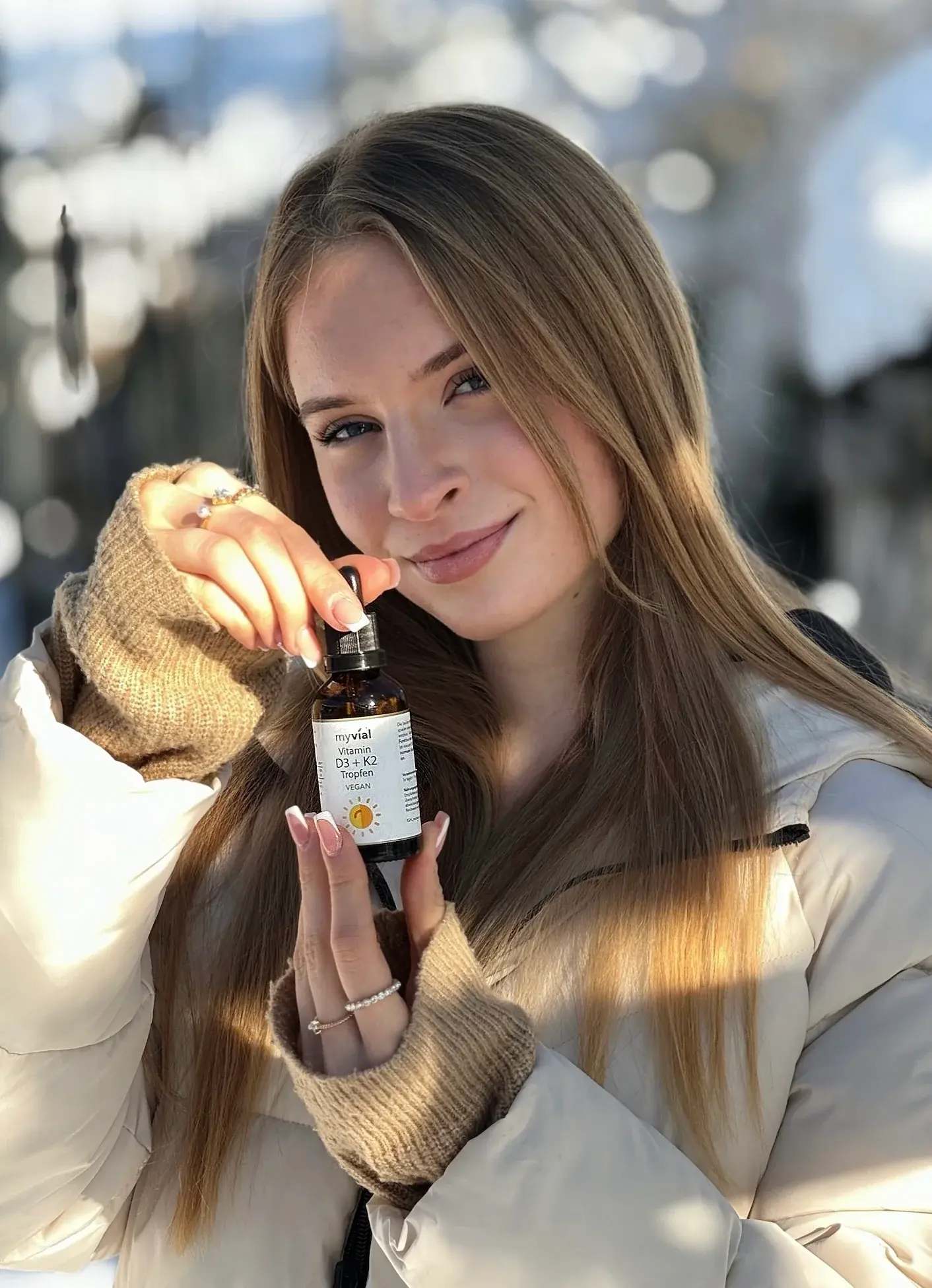 Junge Frau hält myvial Vitamin D3 + K2 Tropfen in die Kamera